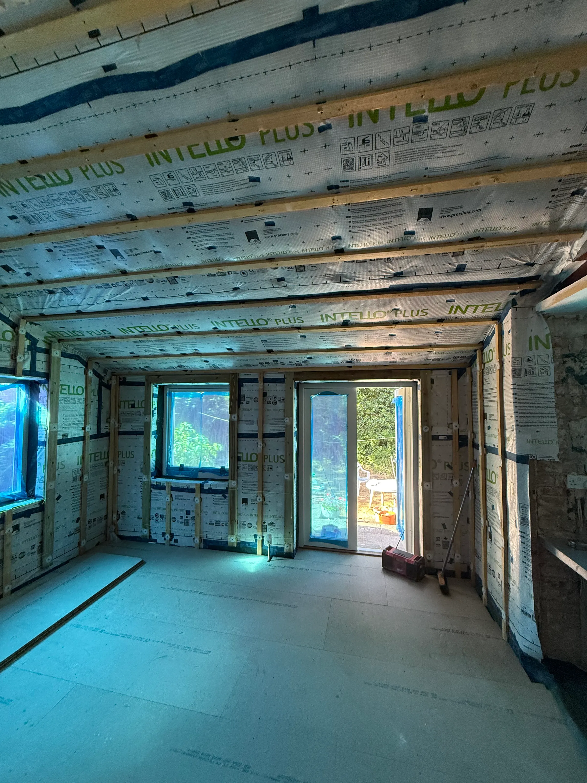A room lined with airtightness membrane, taped at every junction, looking towards patio doors
